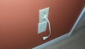 Why does running a power cord behind the wall for a wall-mounted TV violate the electrical code?
